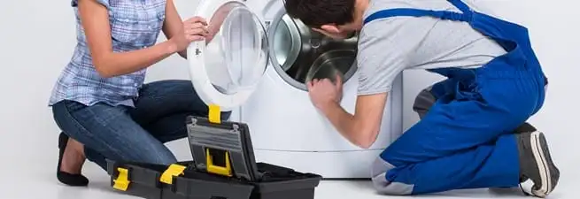 Washer repair technician inspecting a front-load washing machine with tools in Sarasota, FL