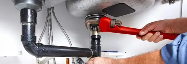 Garbage disposal repair technician tightening the sink drain and disposal connection in Sarasota, FL