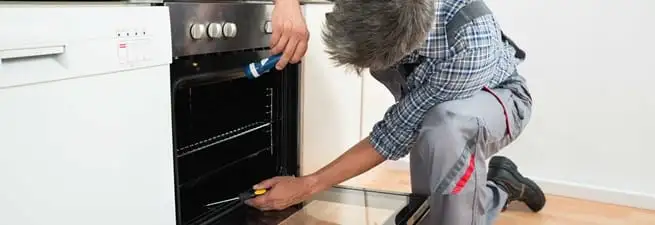 Oven repair technician inspecting and servicing an electric oven in Sarasota, FL