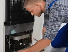 Refrigerator repair technician servicing the compressor and condenser area in Sarasota, FL