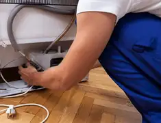 Appliance repair technician fixing refrigerator water line and connections in Sarasota, FL