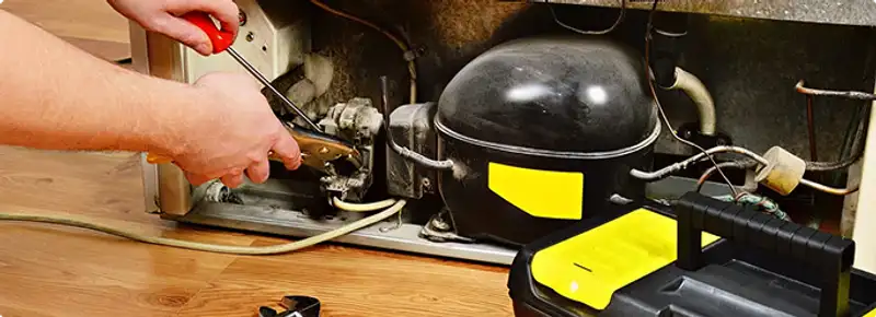 Refrigerator repair technician fixing the compressor and wiring in Sarasota, FL