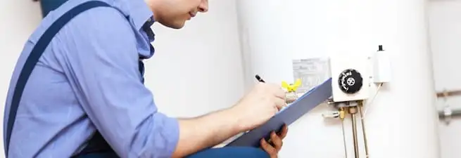 Water heater repair technician inspecting the unit and recording service notes in Sarasota, FL
